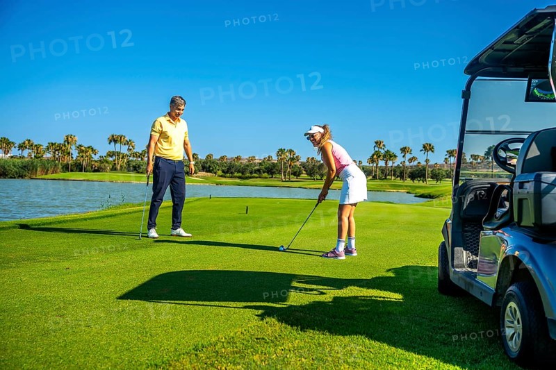 Couple playing golf on a beautiful sunny day, enjoying the sport and the stunning scenery surrounding the course