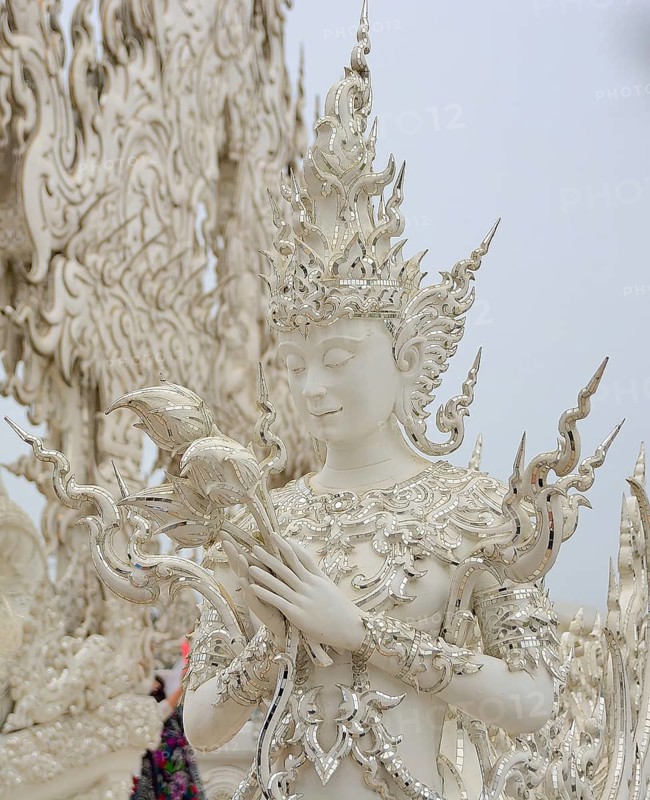 White sculpture holding lotus flowers at the famous wat rong khun, also known as the white temple, in chiang rai, thailand, showcasing intricate details and spiritual symbolism