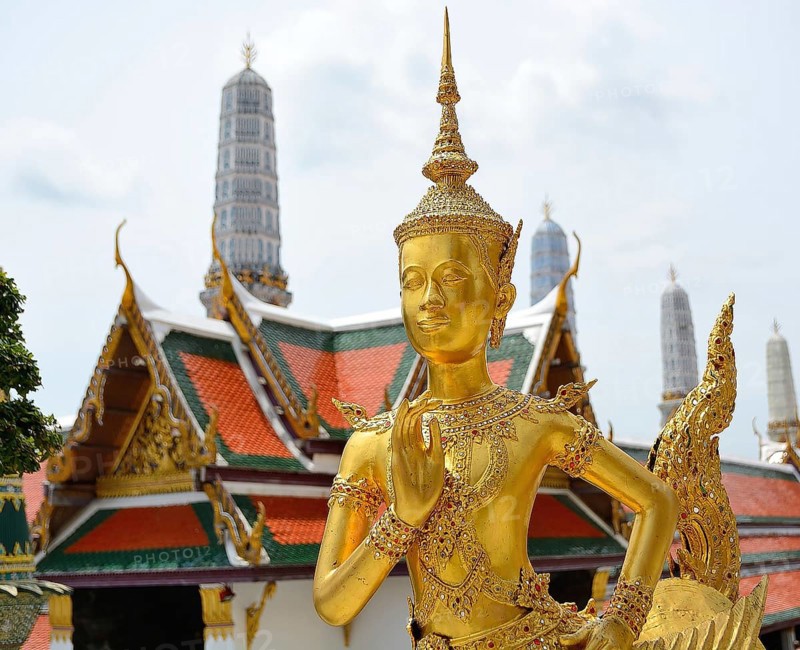 Golden kinnara statue praying with hands joined in a traditional thai greeting, inside the wat phra kaew temple complex in bangkok, thailand