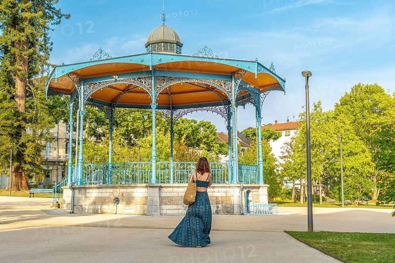 Tourist walking away from a bandstand in salies de bearn, a charming village in the pyrenees atlantiques region of france, enjoying a sunny summer day
