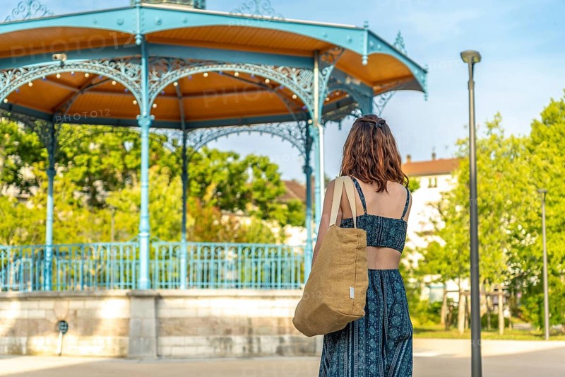 Young woman carrying a shopping bag walking towards a bandstand in salies de bearn, a commune in the pyrenees atlantiques department in south western france