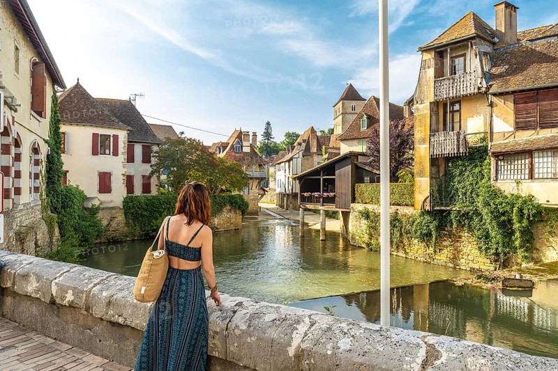 Young woman admiring the saleys river flowing through the picturesque village of salies de bearn, a popular tourist destination in the pyrenees atlantiques region of france