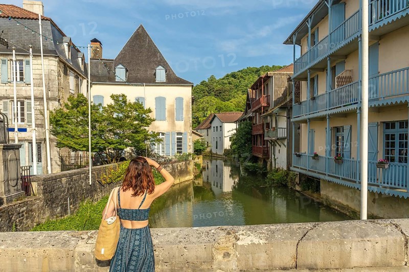 Tourist is enjoying the view of the saleys river and its colorful houses in the charming village of salies de bearn, a popular destination in the pyrenees atlantiques region of france