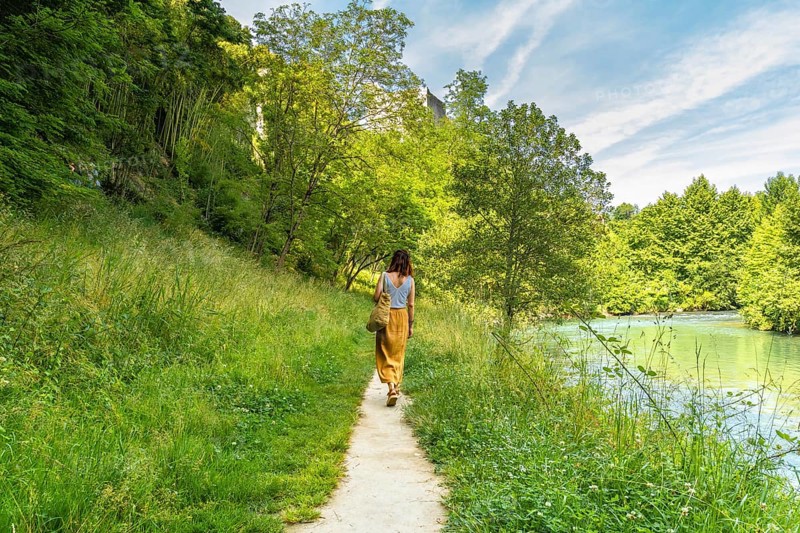 Tourist enjoying a peaceful walk along the gave d'oloron river in sauveterre de bearn, a charming medieval village in the pyrenees atlantiques region of france