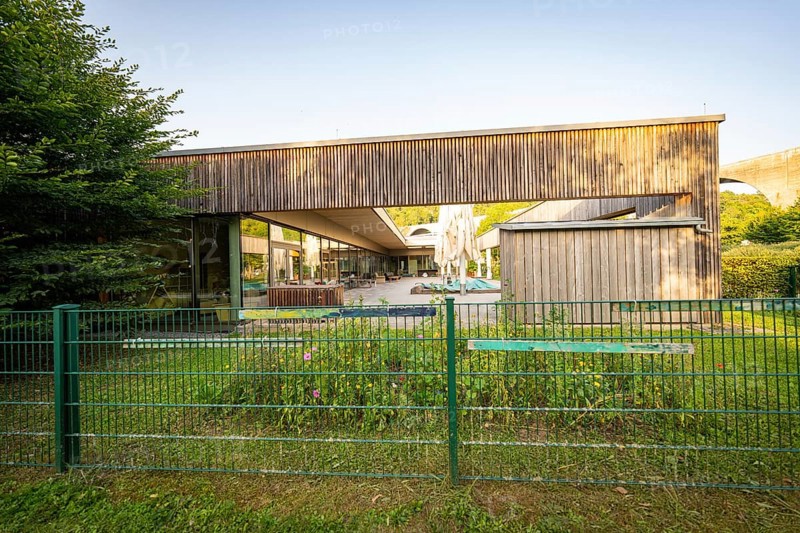 Modern building with wooden wall and garden, surrounded by a green fence in sunshine, Nagold, Landkreis Calw, Schwarzwald, Germany