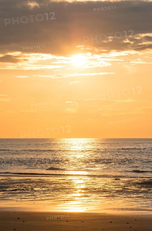 Picturesque sunset over the sea with grey clouds and golden light, sun star, clouds, reflecting light on the shining water and calm atmosphere, warm atmosphere, sea in soft colours, peaceful, orange and gold, wide horizon, sandy beach, mudflats in the foreground, cloud gap, dark clouds, calm sea, island dune, Helgoland, district Pinneberg, Schleswig-Holstein, North Sea, Germany