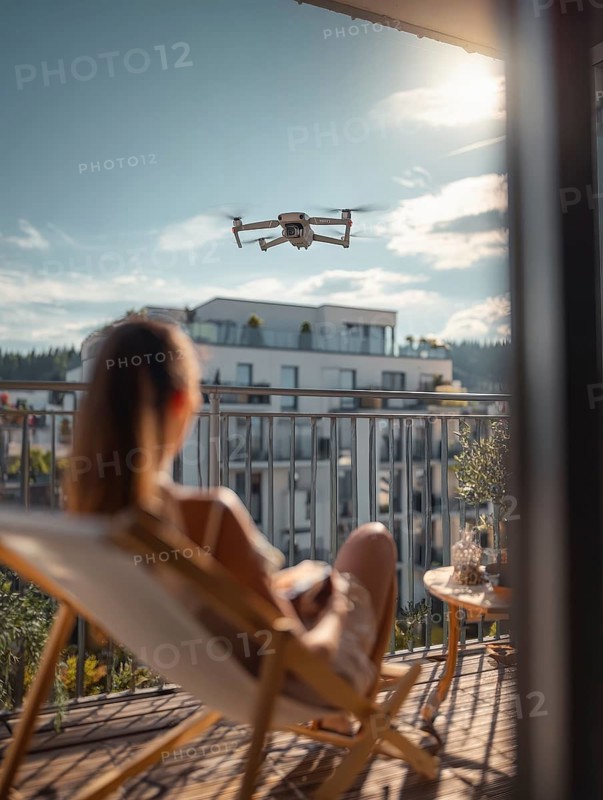 Ein Fernpilot steuert sein Quadrocopter, Drohne in einem dicht besiedeltem Wohngebiet und nähert sich sehr nahe an eine Person auf einer Terrasse um illegale Videoaufnahmen oder Fotos zu erstellen, Symbolbild für unbefugtes Fotografieren von Personen, innerhalb eines geschützten Bereiches, Verletzung der Privatsphäre, Persönlichkeitsrechte, Missachtung von Flugverbotszonen, Datenschutz, AI generiert, AI generated