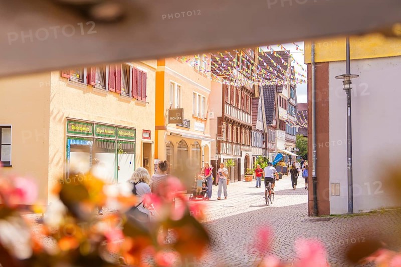 Lively street in a charming old town with cyclists and passers-by, surrounded by historic houses, small town pearl Calw, Black Forest, Germany