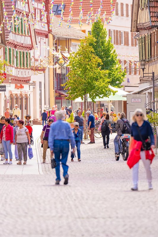 People stroll through a charming, sunny pedestrian zone in an old town with half-timbered houses, small town pearl Calw, Black Forest, Germany