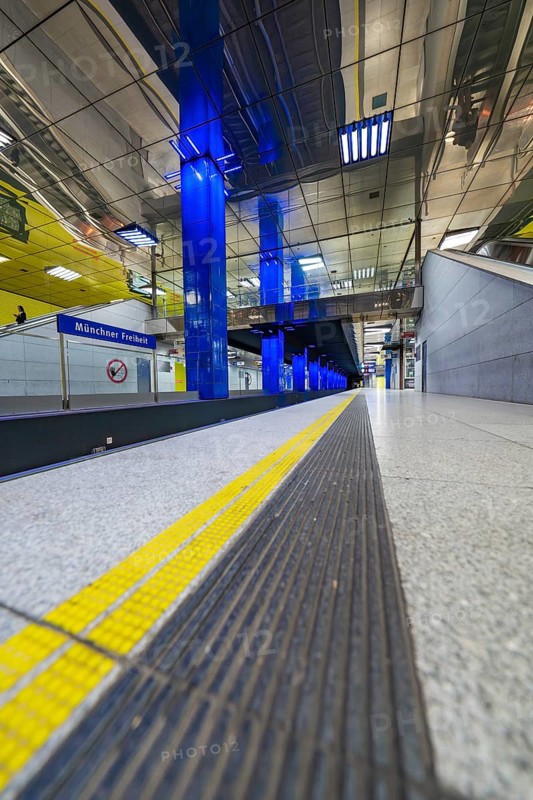 Modern underground station with blue light columns and yellow floor markings, Munich, Germany