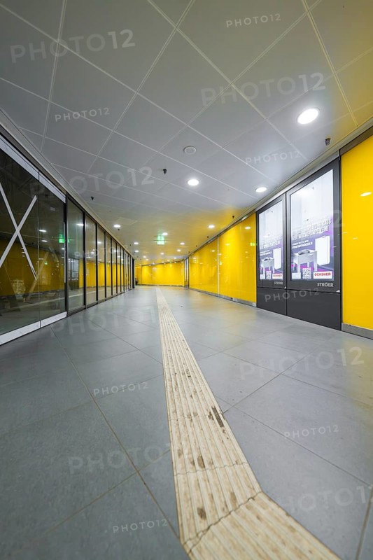 A modern station corridor with yellow walls and a grey floor conveys cleanliness, Munich, Germany
