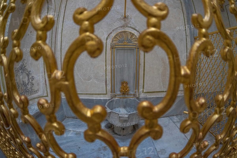 Ornate golden gate protecting a marble fountain inside a historical building in istanbul, turkey, showcasing the rich history and architecture of the city