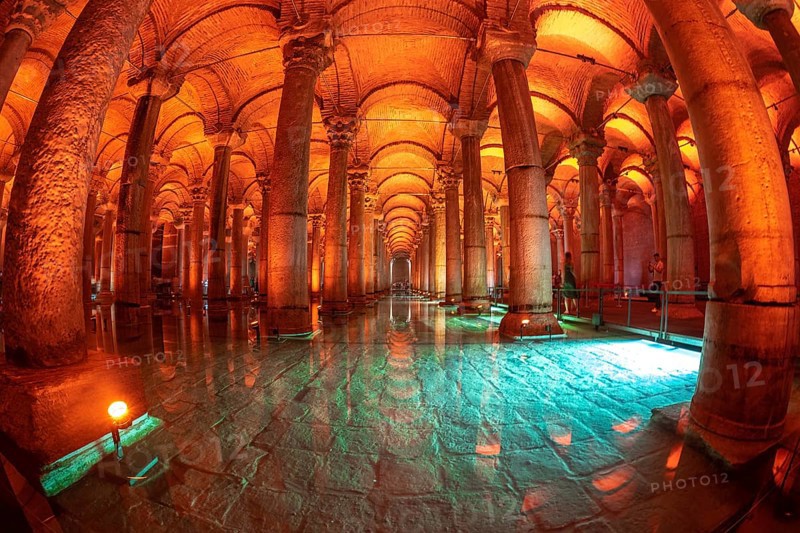 The basilica cistern, an ancient underground water reservoir in istanbul, turkey, is illuminated with orange and green lights reflecting on the turquoise water