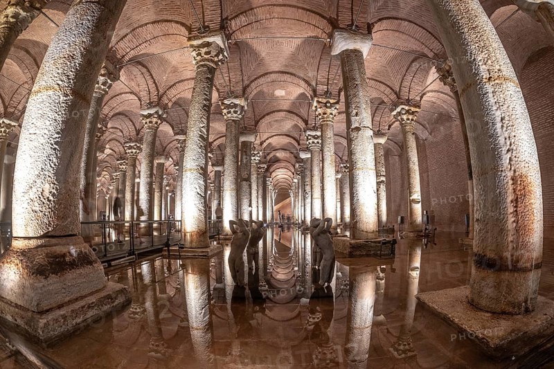 Ancient basilica cistern with many columns reflecting on water surface with sculptures and illuminated lights in istanbul, turkey