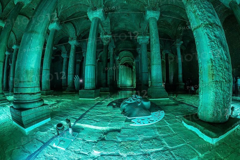 Green lights illuminating ancient columns, medusa's head and hand sculptures in basilica cistern, a famous landmark in istanbul, turkey
