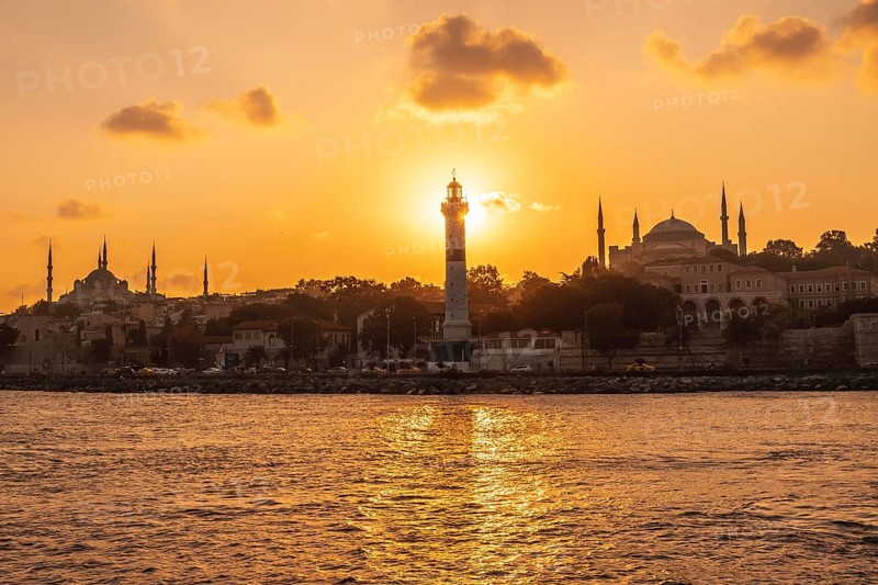 Scenic sunset over istanbul with prominent lighthouse, mosque and hagia sophia silhouettes, showcasing the city's beauty and rich history