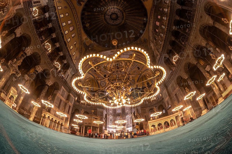 Fisheye view of tourists visiting the magnificent interior of hagia sophia, showcasing its stunning architecture, intricate mosaics, and impressive chandeliers
