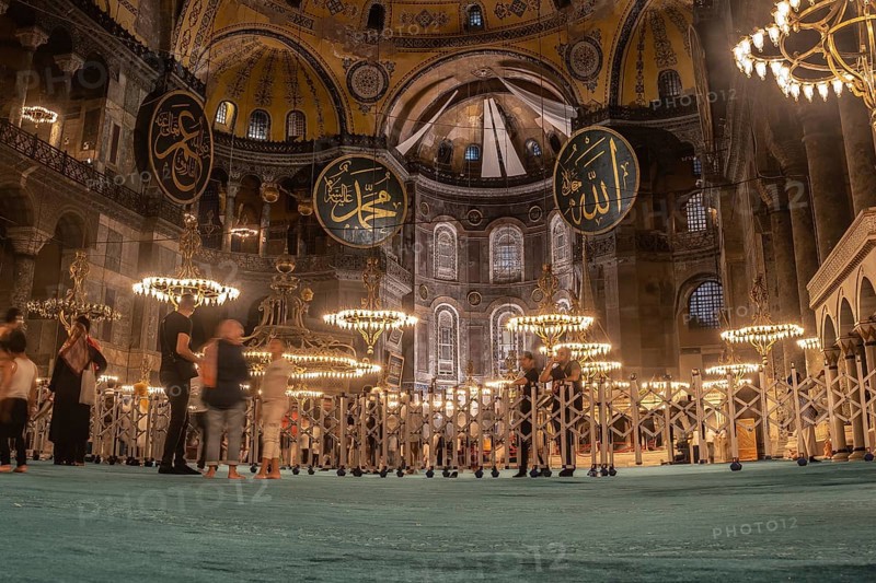 Tourists admiring the interior of the magnificent hagia sophia in istanbul, turkey, illuminated by beautiful chandeliers at night