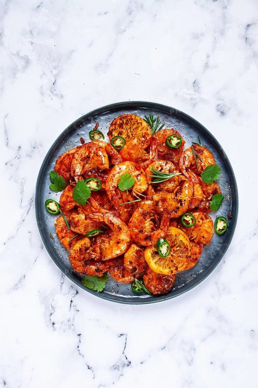 Grilled shrimp, unpeeled, headless, with spices, on a marble table, homemade, no people