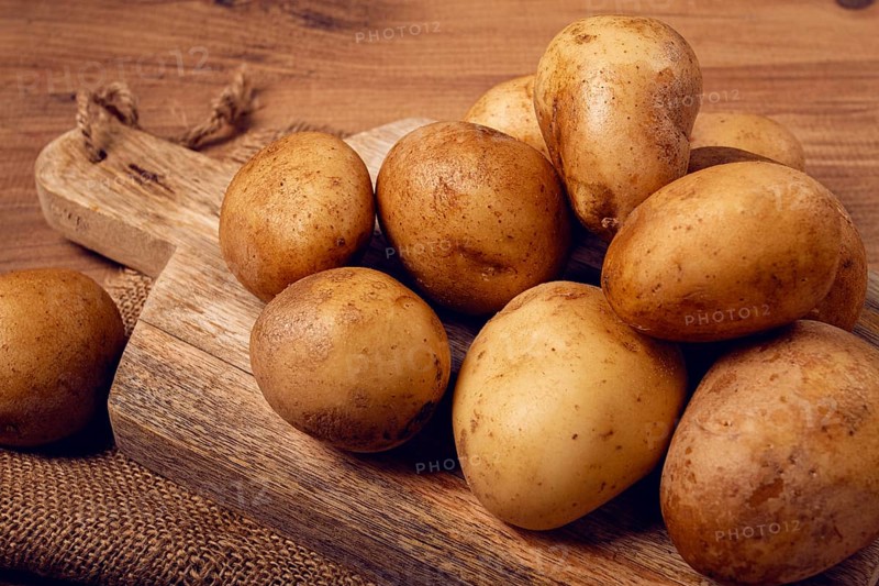 Raw potatoes, scattered on a chopping board, close-up, no people