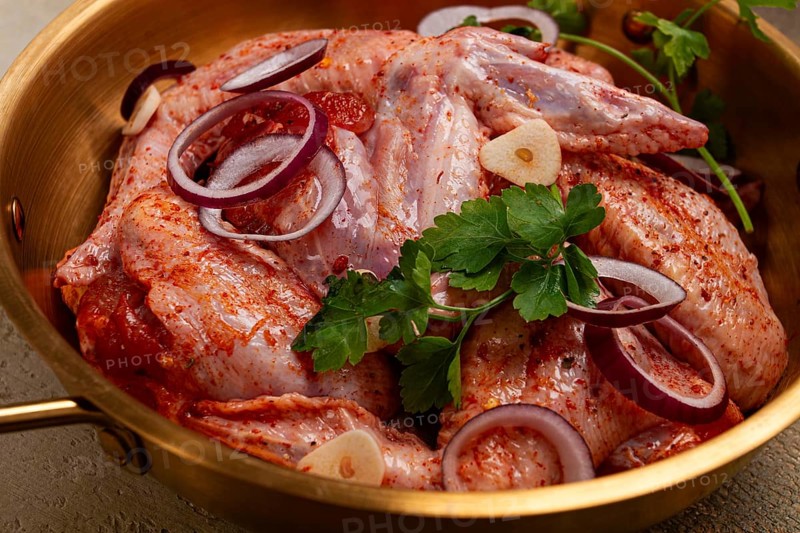 Chicken wings, in a brass saucepan, ready for cooking, grilling or baking, in a home kitchen, no people