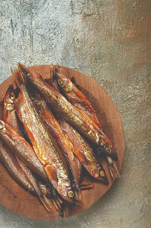 Cold smoked capelin, on a wooden bowl, top view, no people