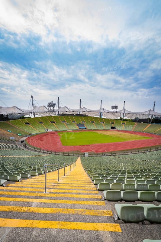 Symmetrical view of a stadium from a staircase with red running track and green stands, Olympic Park, Munich, Germany