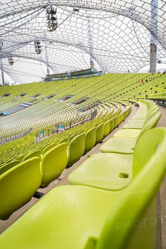 Close-up of empty green seats with a view of a modern glass roof, Olympiapark, Munich, Germany