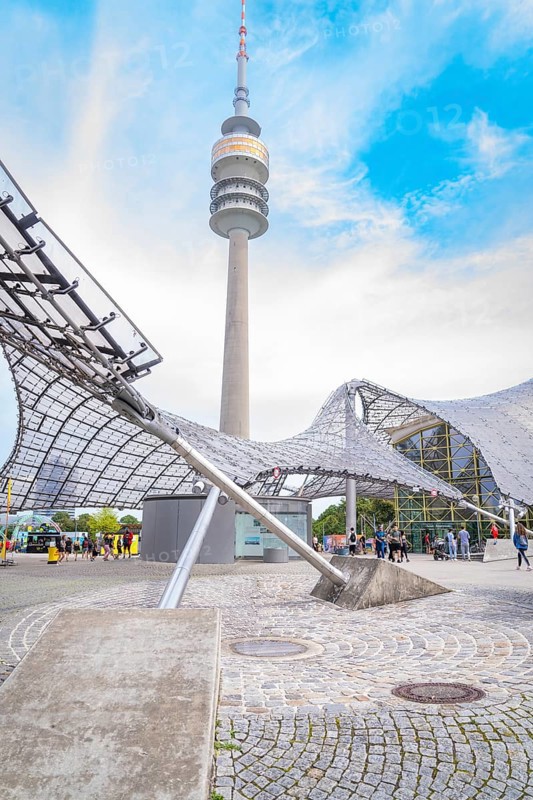 Impressive architecture below a television tower with modern design under a blue sky, Olympic Park, Munich, Germany