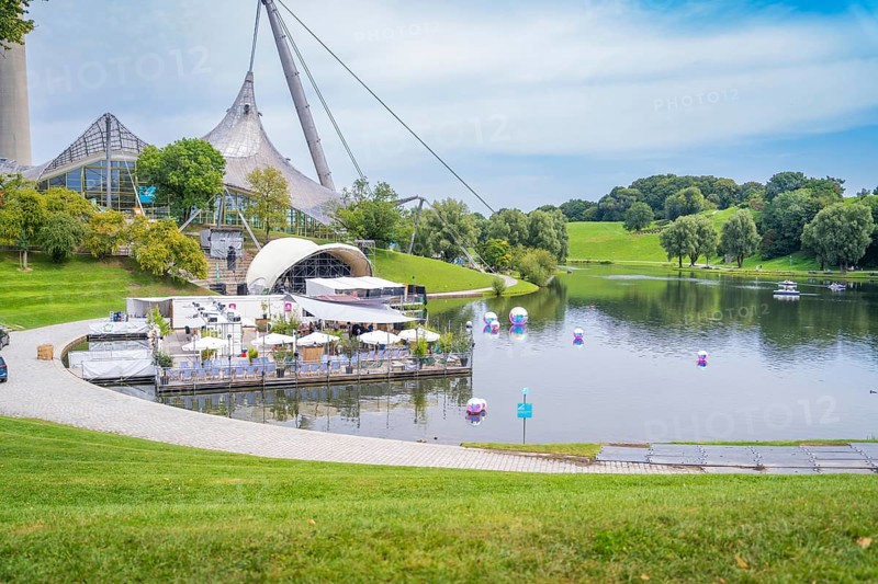 Idyllic landscape with lake, modern pavilion and grassy hills, Olympic Park, Munich, Germany