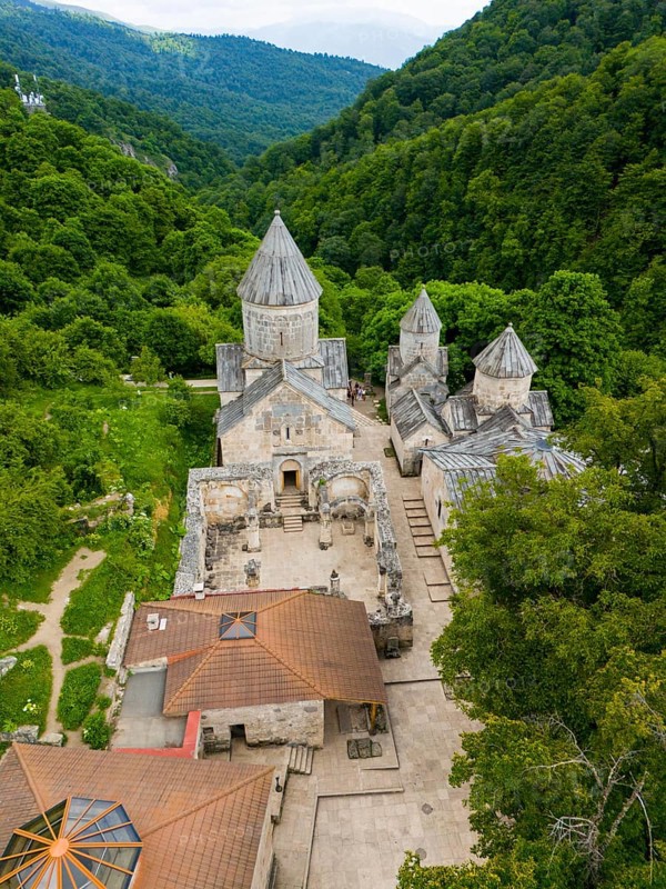 Aerial view of an old monastery complex surrounded by lush green forests, showing historical architecture, aerial view, Haghartsin Monastery, Hagarzin, left church Surp Astvatsatsin, right church Surp Stepanos and Surp Grigor and a gavit, Tavush Province, Armenia