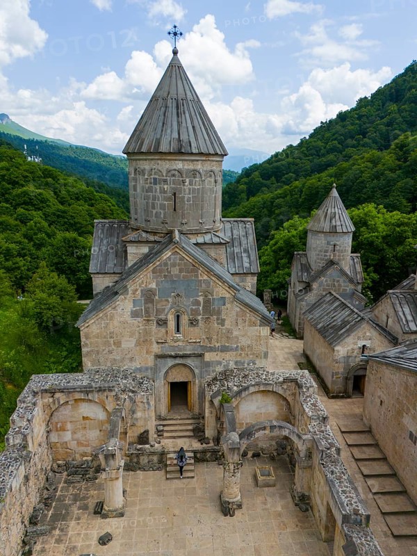 Sacred building with old stone walls, embedded in a wooded landscape under a clear sky, aerial view, Haghartsin Monastery, Hagarzin, on the left Surp Astvatsatsin Church, on the right Surp Stepanos Church, Tavush Province, Armenia
