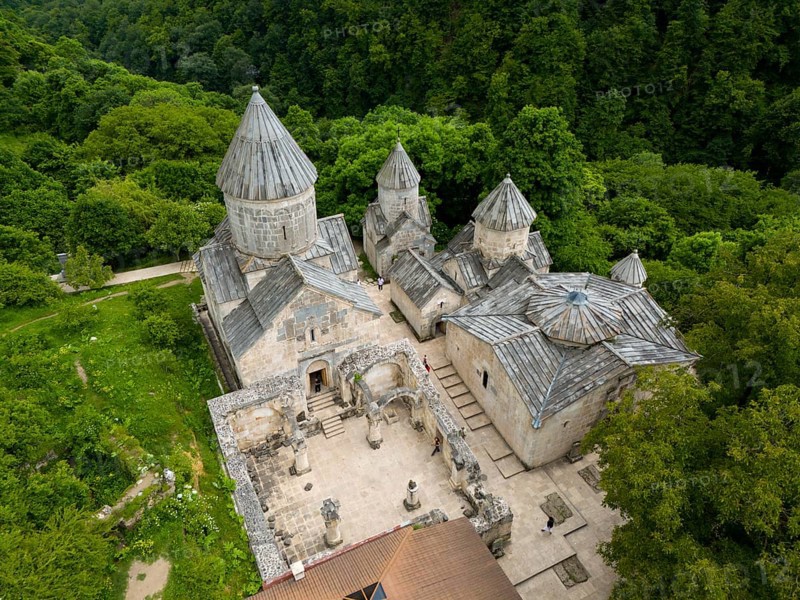 Aerial view of a historic monastery with striking stone architecture, surrounded by forest, aerial view, Haghartsin Monastery, Hagarzin, Surp Astvatsatsin church on the left, Surp Stepanos and Surp Grigor churches and a gavit on the right, Tavush Province, Armenia