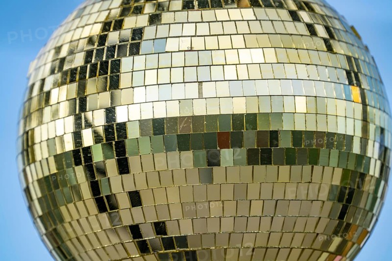 Golden disco ball, small mirrors, distributed like a mosaic, reflect light and create lighting effects in a room