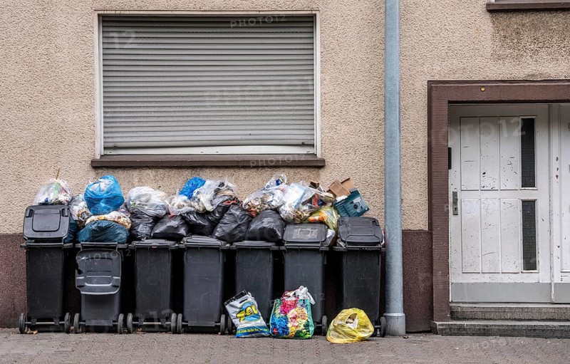 Overflowing rubbish bins in front of a residential building in Gelsenkirchen, North Rhine-Westphalia, Germany