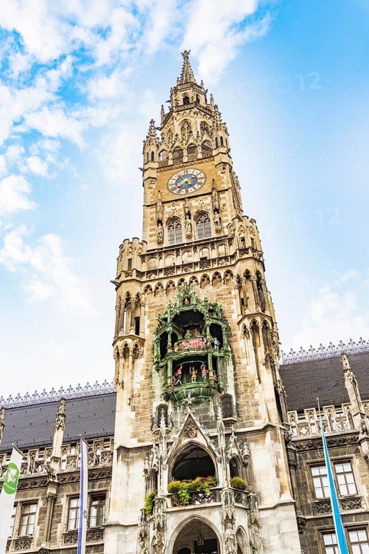 Detailed tower of the town hall with clock and figures under a blue sky, Munich, Germany