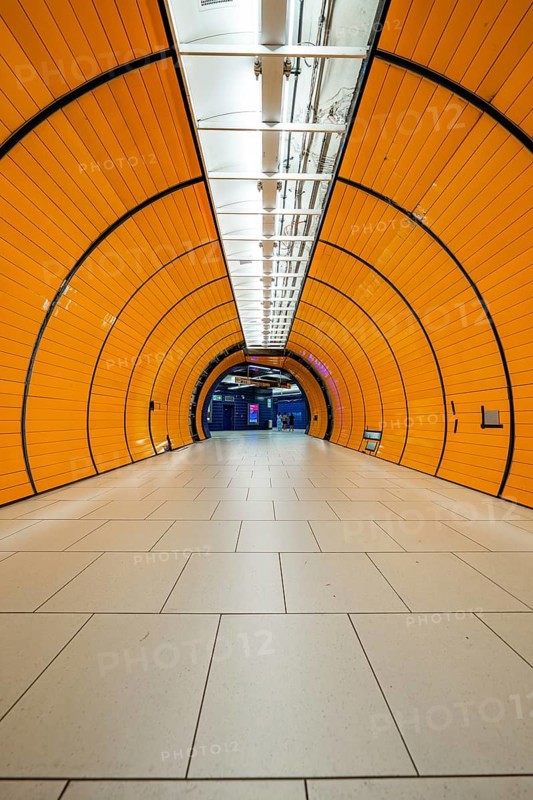 Long, illuminated underground railway tunnel in bright orange, leading into the distance, Marienplatz Munich, Germany