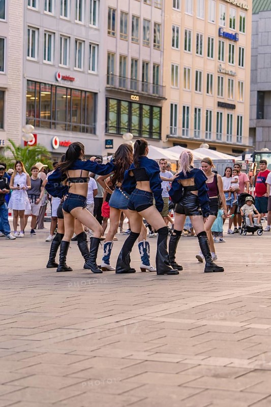 Dance group performs outdoors against an urban backdrop, surrounded by spectators, Munich, Germany