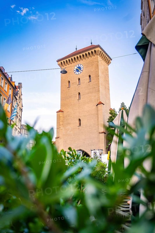 Historic clock tower in an urban setting with blue sky, Munich, Germany
