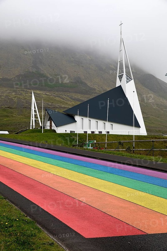 Street painted in the colours of the rainbow and the fish-shaped church designed by Hákon Hertervig, Ólafsvík, Snæfellsnes, Iceland