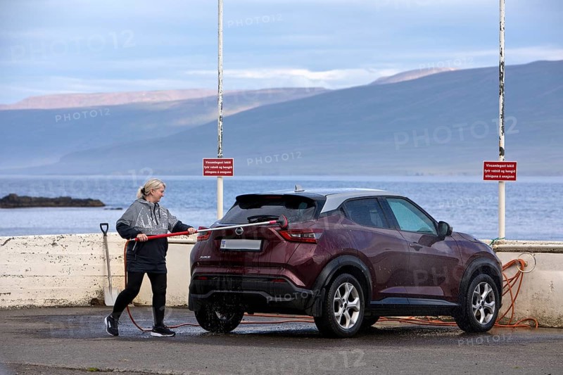 Washing the car with the free water brush at the petrol station by the Vopnafjördur fjord, East Iceland, Iceland