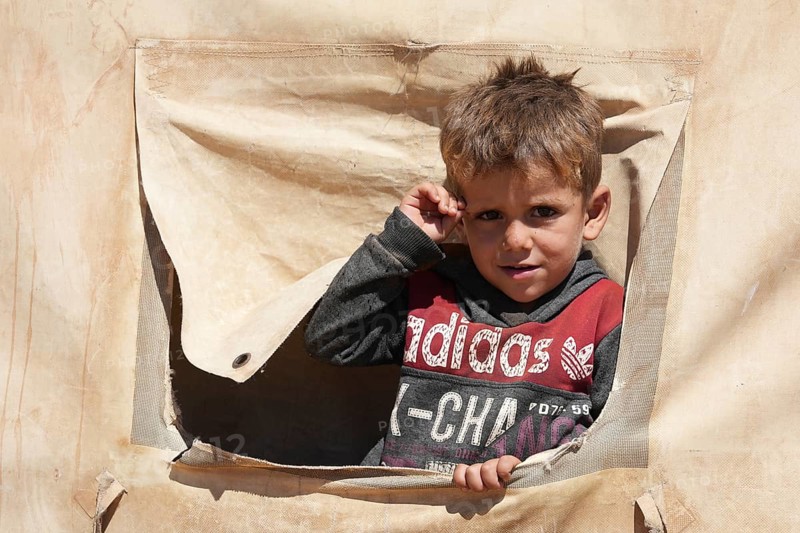 A portrait of a sweet Syrian girl looking through a peephole in a makeshift refugee tent. Aleppo, Syria, July 19, 2023, Aleppo, Syria