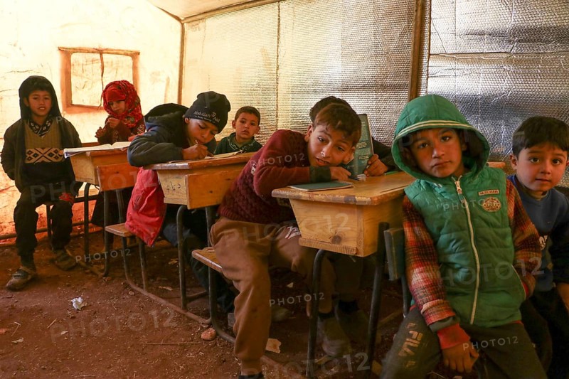 Syrian refugee children sitting inside a tent classroom, receiving basic education despite displacement and conflict. Aleppo, Syria January 18, 2022, Aleppo, Syria