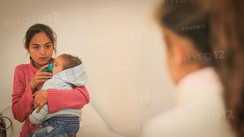 A doctor examining a displaced Syrian child inside a mobile clinic at a refugee camp. Aleppo, Syria February 9, 2019, Aleppo, Syria