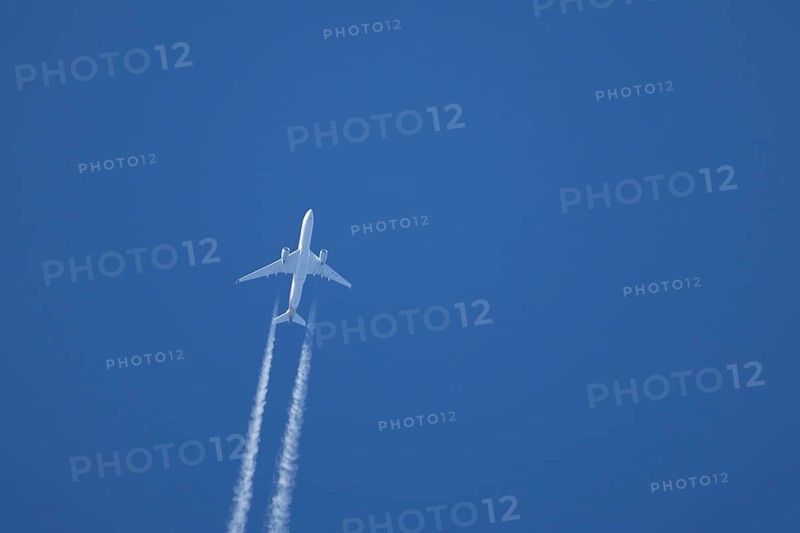 Airbus A350-900 passenger jet aircraft of Singapore airlines flying with a vapour trial or contrail behind in a blue sky, England, United Kingdom