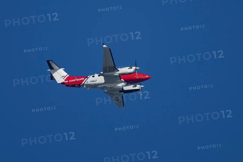 Beech King Air 350 light aircraft of the UK HM Coastguard flying in a blue sky, England, United Kingdom