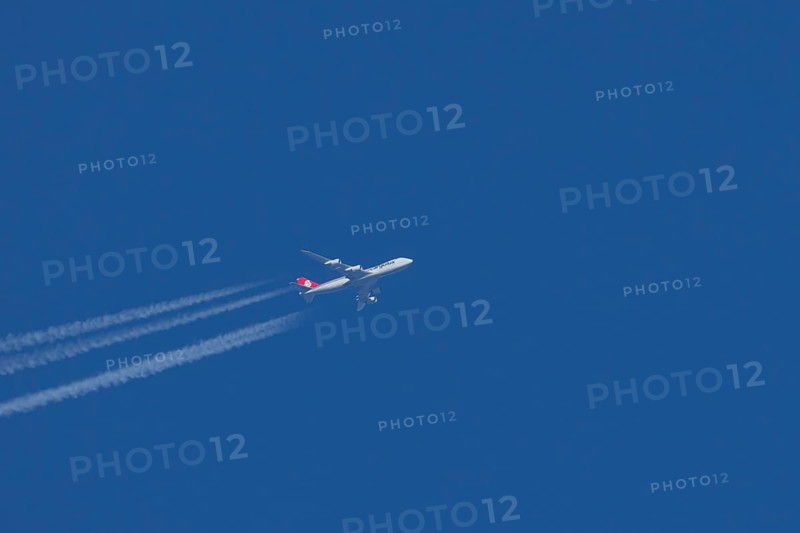 Boeing 747 jumbo jet cargo aircraft of Cargolux airlines with a vapour trail or contrail flying in a blue sky, England, United Kingdom