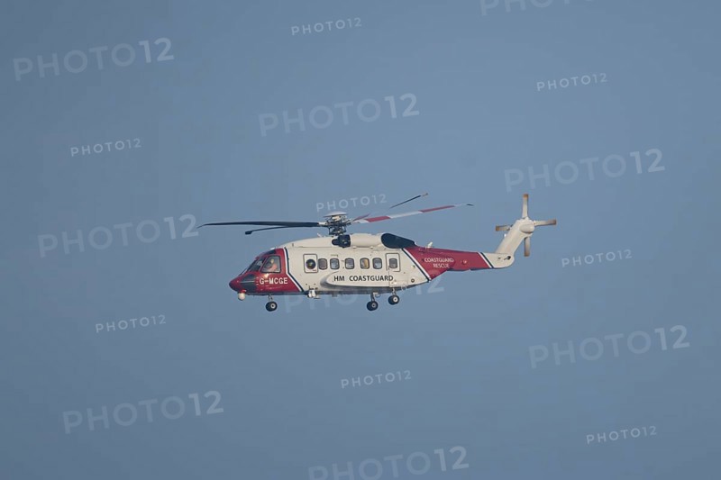Sikorsky S-92A helicopter of the UK HM Coastguard flying in a blue sky, England, United Kingdom