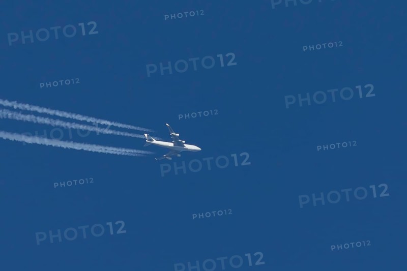 Boeing 747 jumbo jet cargo aircraft with a vapour trail or contrail flying in a blue sky, England, United Kingdom