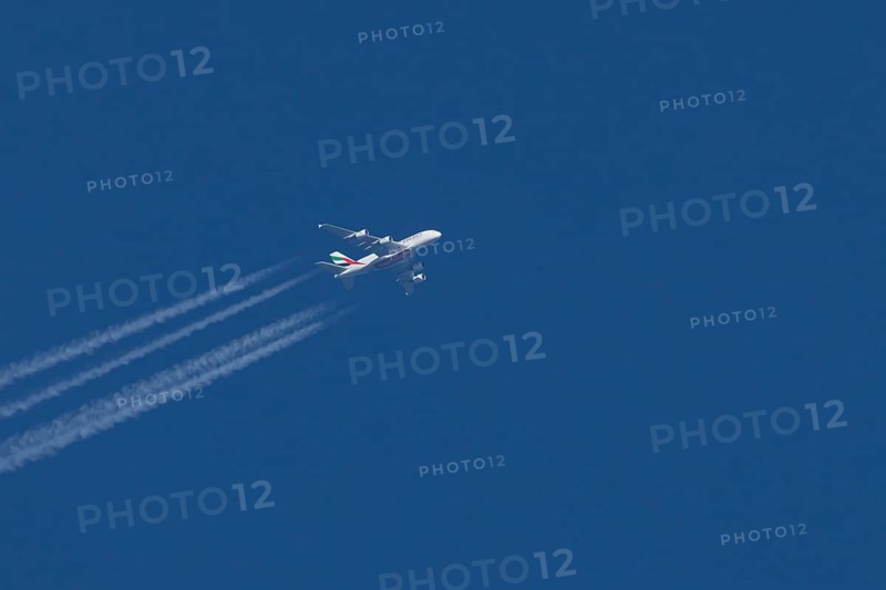 Airbus A380 jet passenger aircraft of Emirates airlines with a vapour trail or contrail flying in a blue sky, England, United Kingdom
